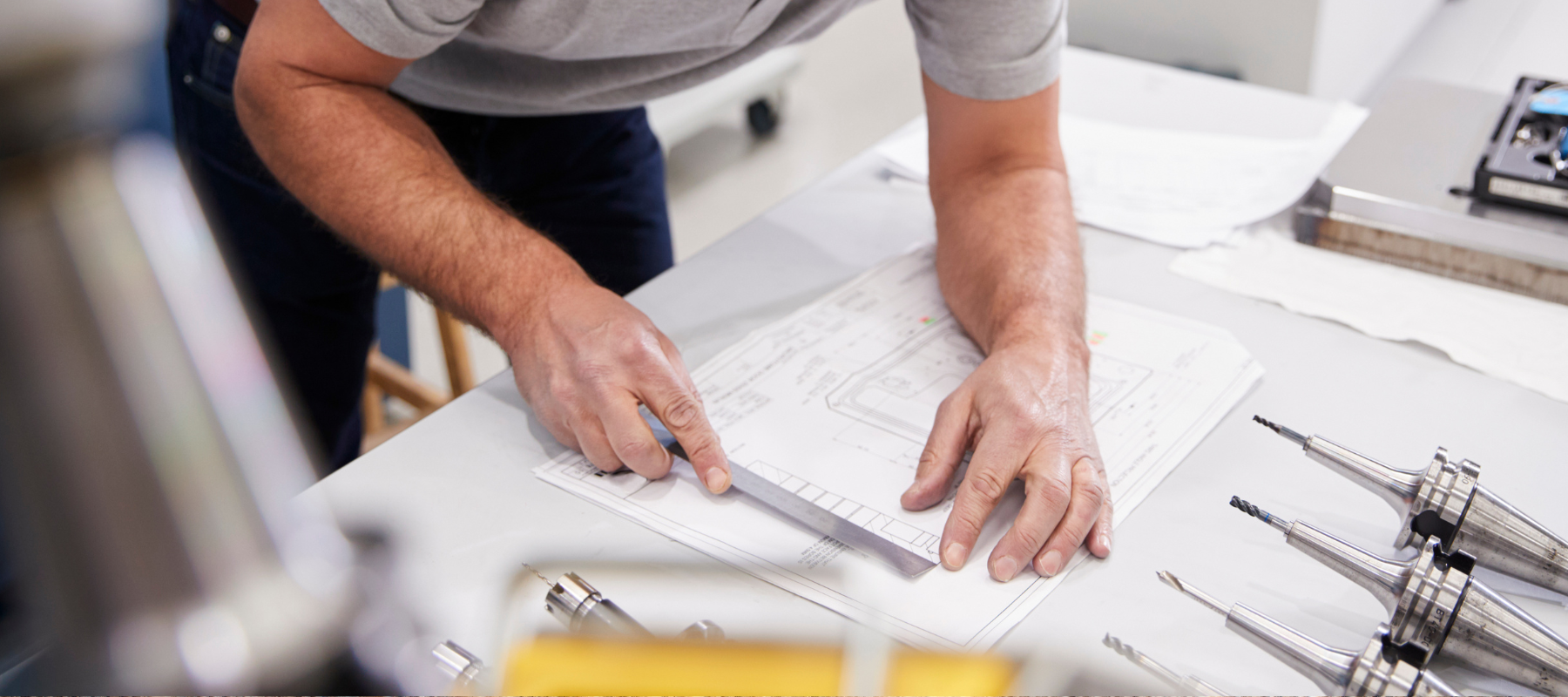 Contractor measuring blueprints that are laid out on his desk with a ruler